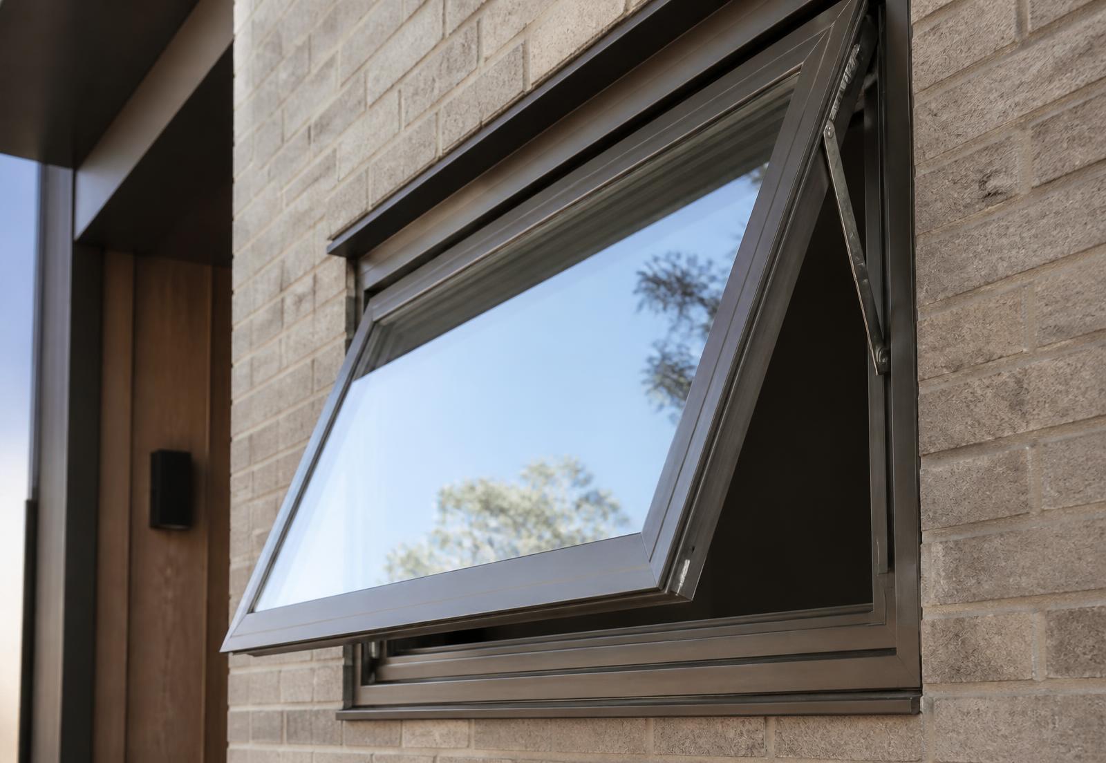 Bronze aluminum casement window cranked open on a brick facade