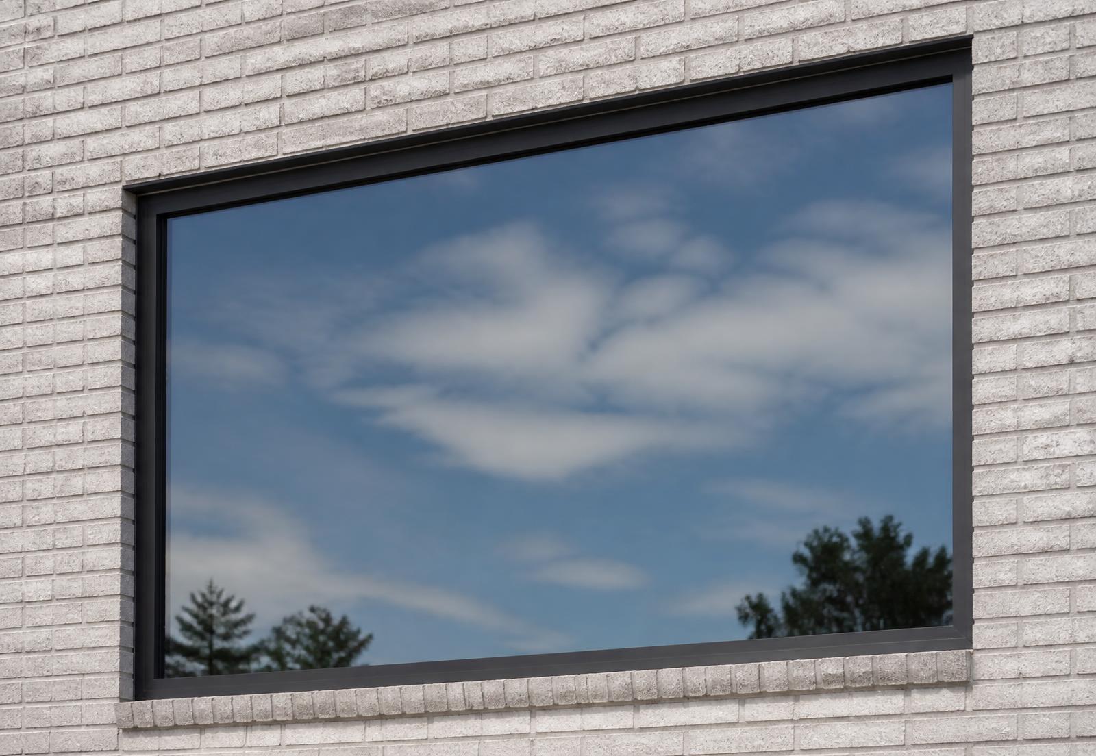 Large fixed aluminum picture window with no hardware set in a light masonry wall opening